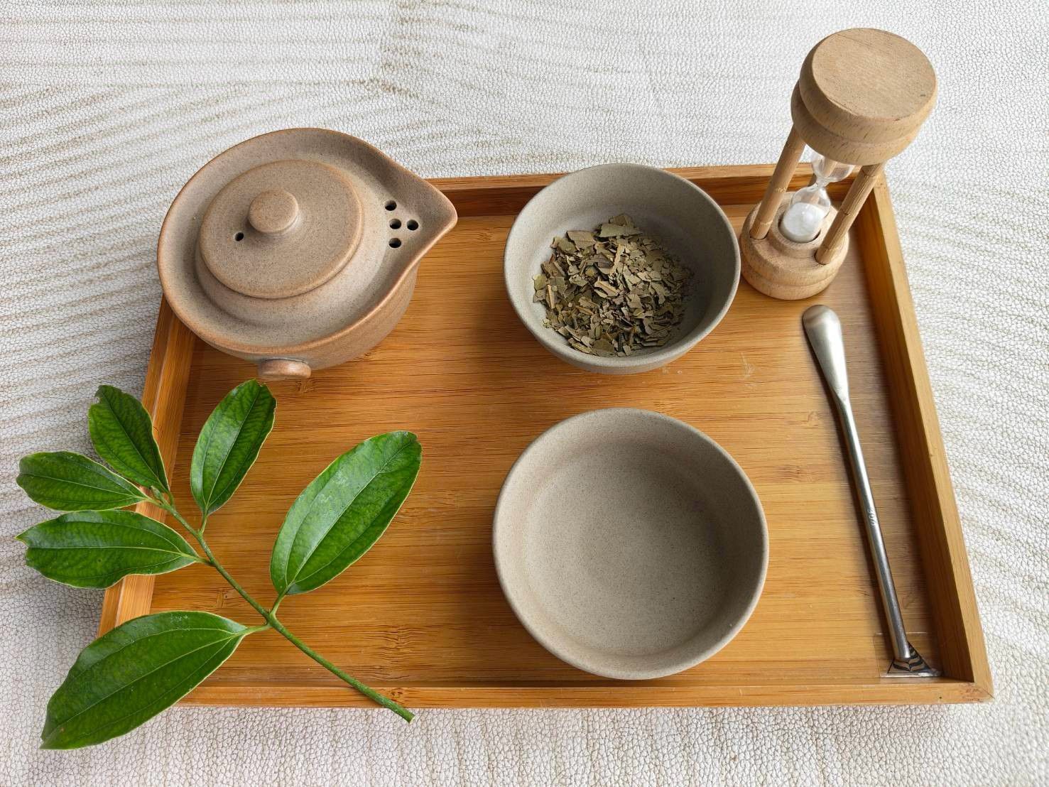 木托盤上的茶具、茶葉與一枝土肉桂葉